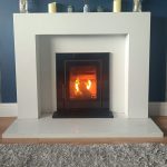A Wave 5 insert cassette stove installed in a white marble fireplace and lighting