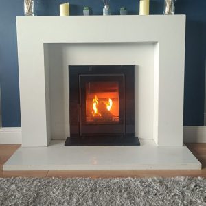 A Wave 5 insert cassette stove installed in a white marble fireplace and lighting